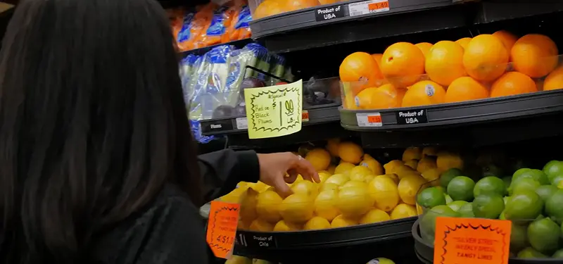 Woman picking up lemons in the fruit aisle