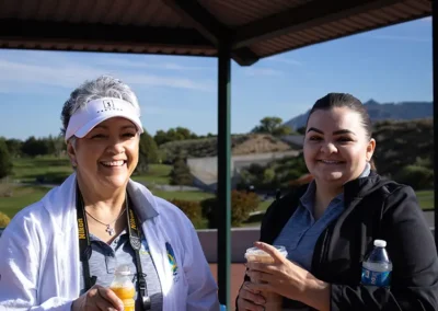 Two golf tournament participants standing under a shade structure.