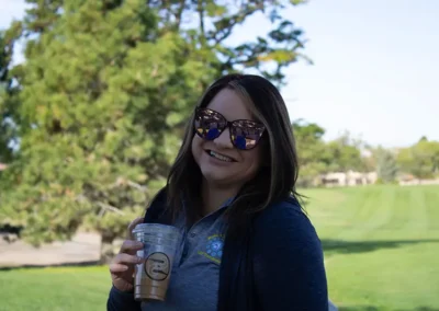Golf tournament participant standing on the golf course with coffee in hand.