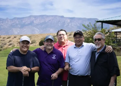 Five golf tournament participants standing on the golf course.