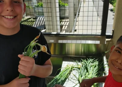 Kids holding green onions from the community garden.