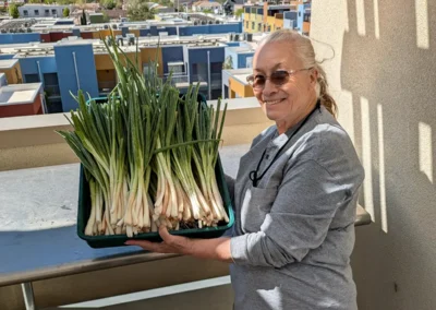 Woman holding stacks of green onions in a bin.