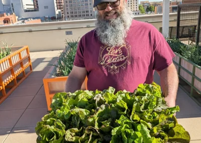 Man holding a pile of leafy greens in a bin.